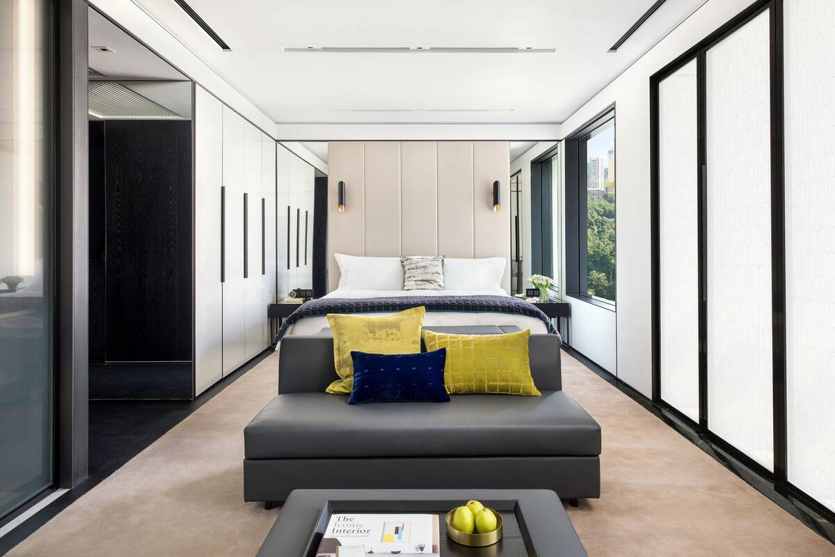 A modern hotel room with a large bed, a sofa, and a coffee table.
