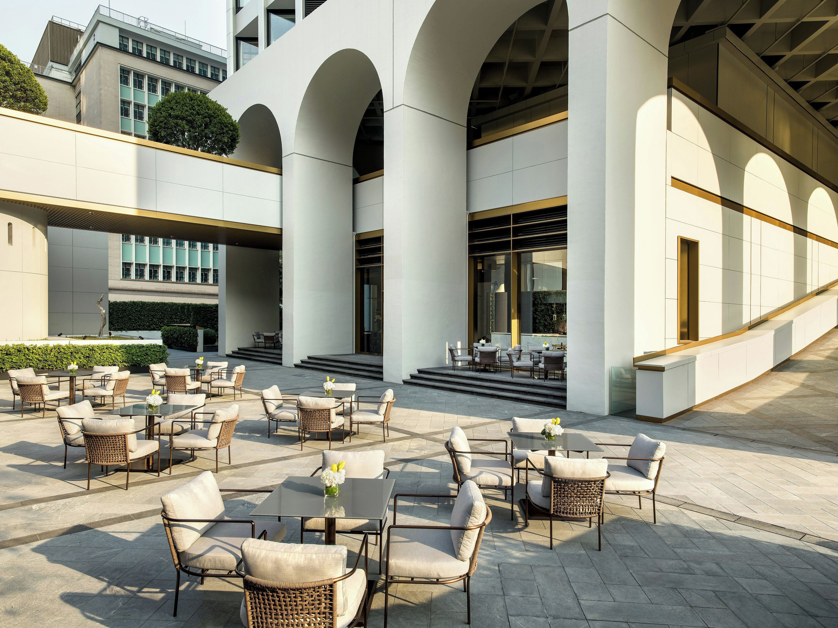 A modern building with a covered outdoor seating area featuring wicker chairs and tables.