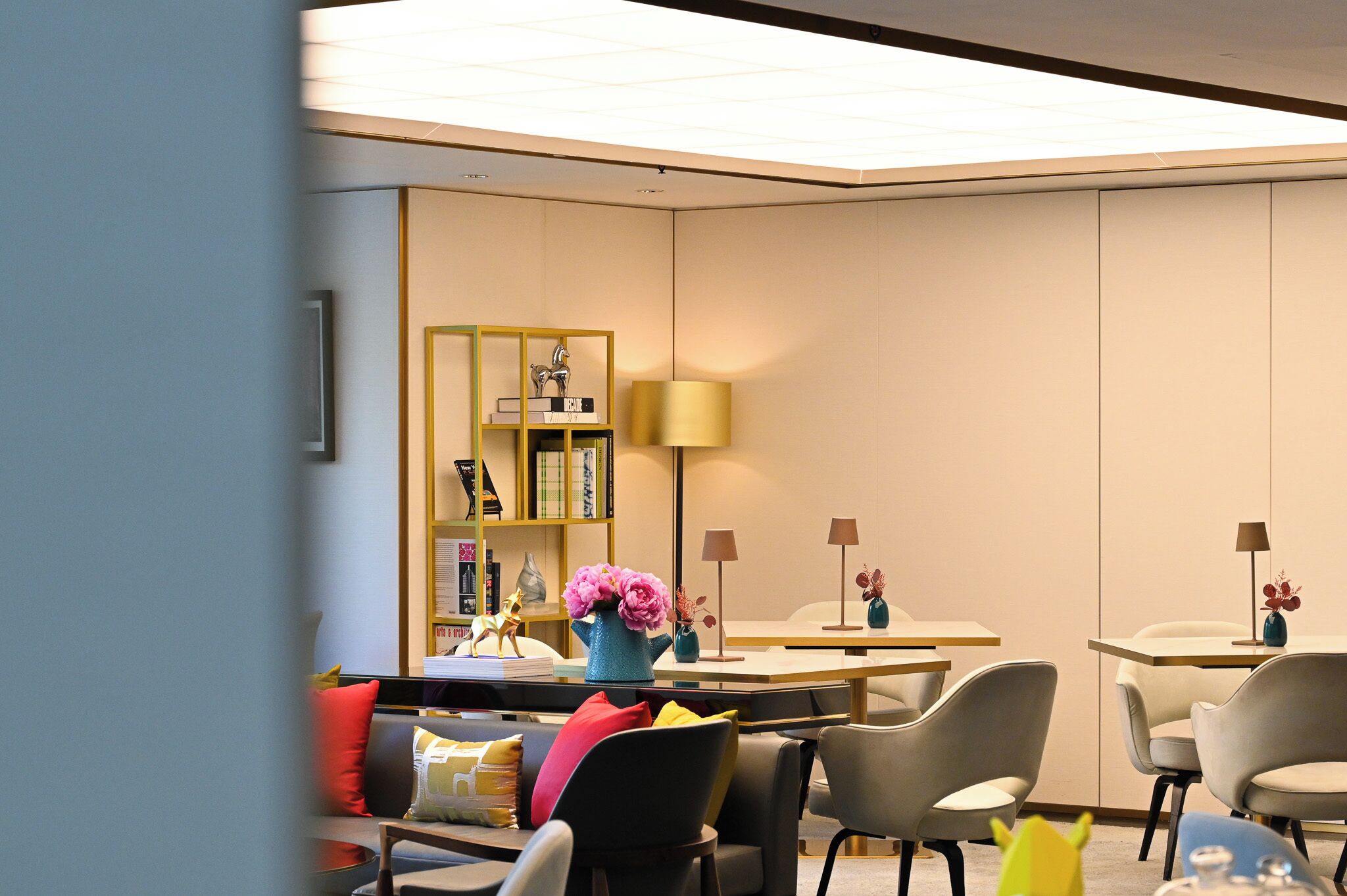 Ett modernt hotellrum med en sittgrupp, en bokhylla och ett bord med lampor.