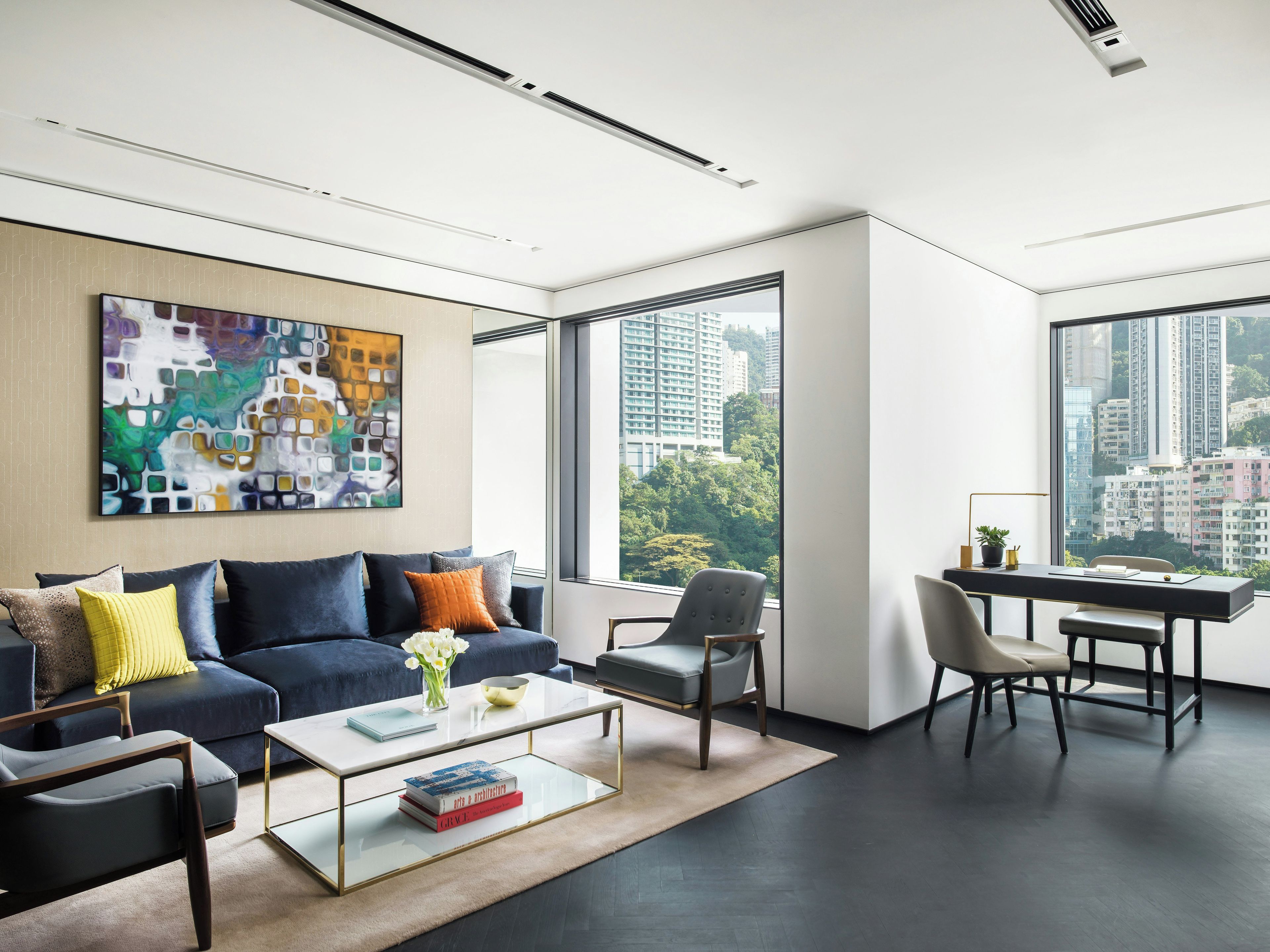 A modern living room with a sofa, coffee table, and a desk with chairs.