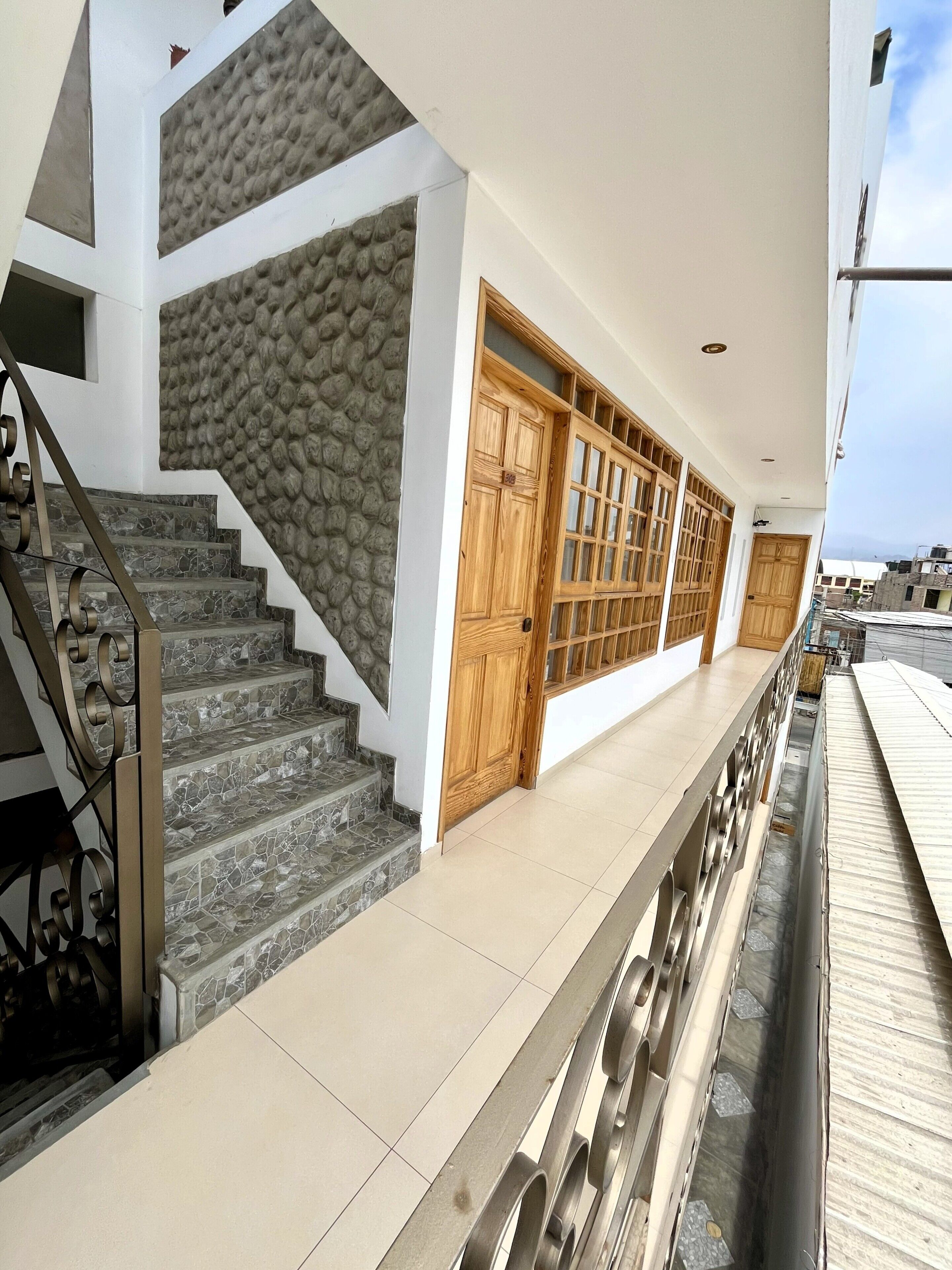 Un edificio moderno con una escalera de piedra, puertas de madera y una barandilla de metal.