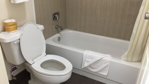 Une salle de bain équipée de toilettes, d’une baignoire et d’un rideau de douche.