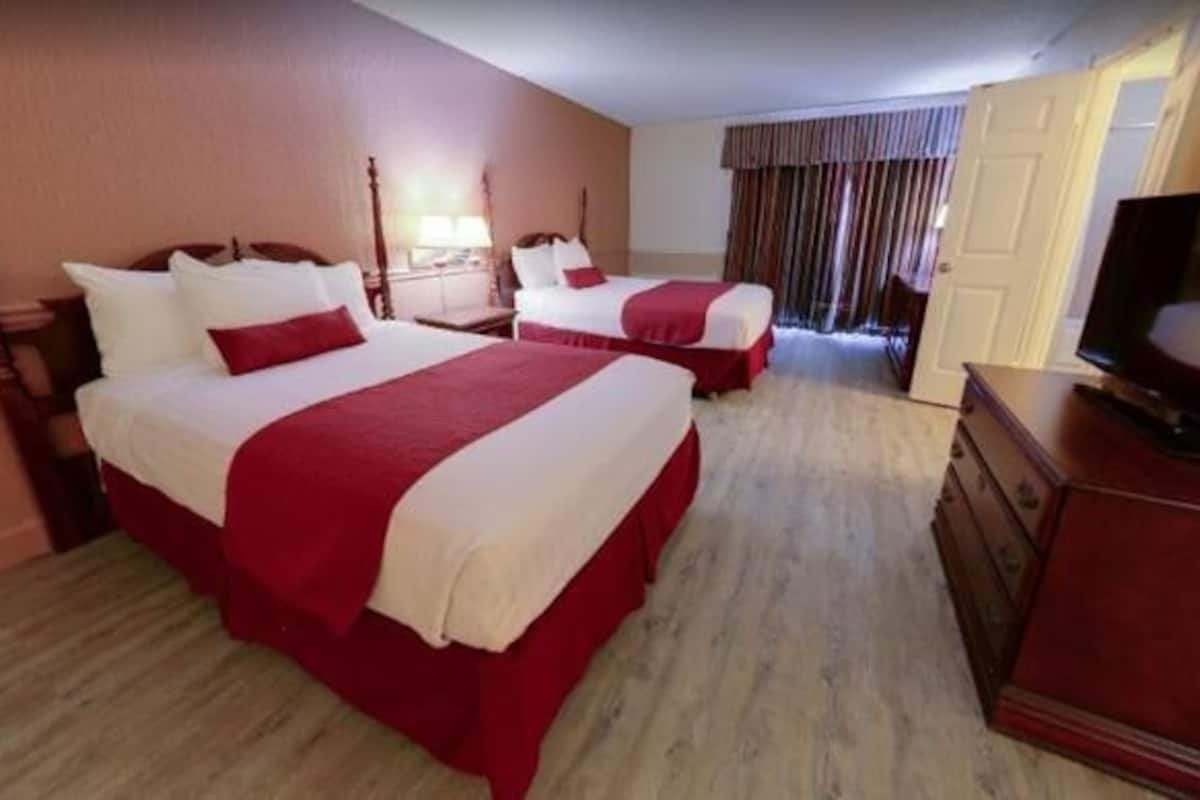 A hotel room with two beds, a TV, and a dresser.