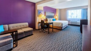 Une chambre d’hôtel avec un lit, un bureau, un canapé et une chaise.