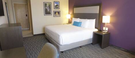 Una habitación de hotel con una cama grande, dos lámparas de noche, un escritorio y una silla.