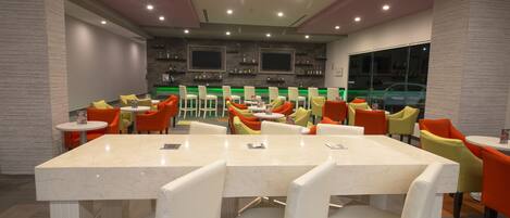 A modern restaurant with a marble bar and bright orange chairs.