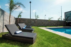 A poolside area with lounge chairs and a stone wall.
