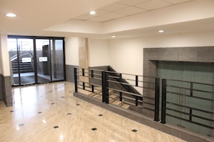 Un interior moderno con una escalera, una puerta de vidrio y piso de baldosas.