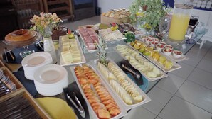 A buffet with various food items and a drink dispenser. - Pousada Marinamarela (Penha)