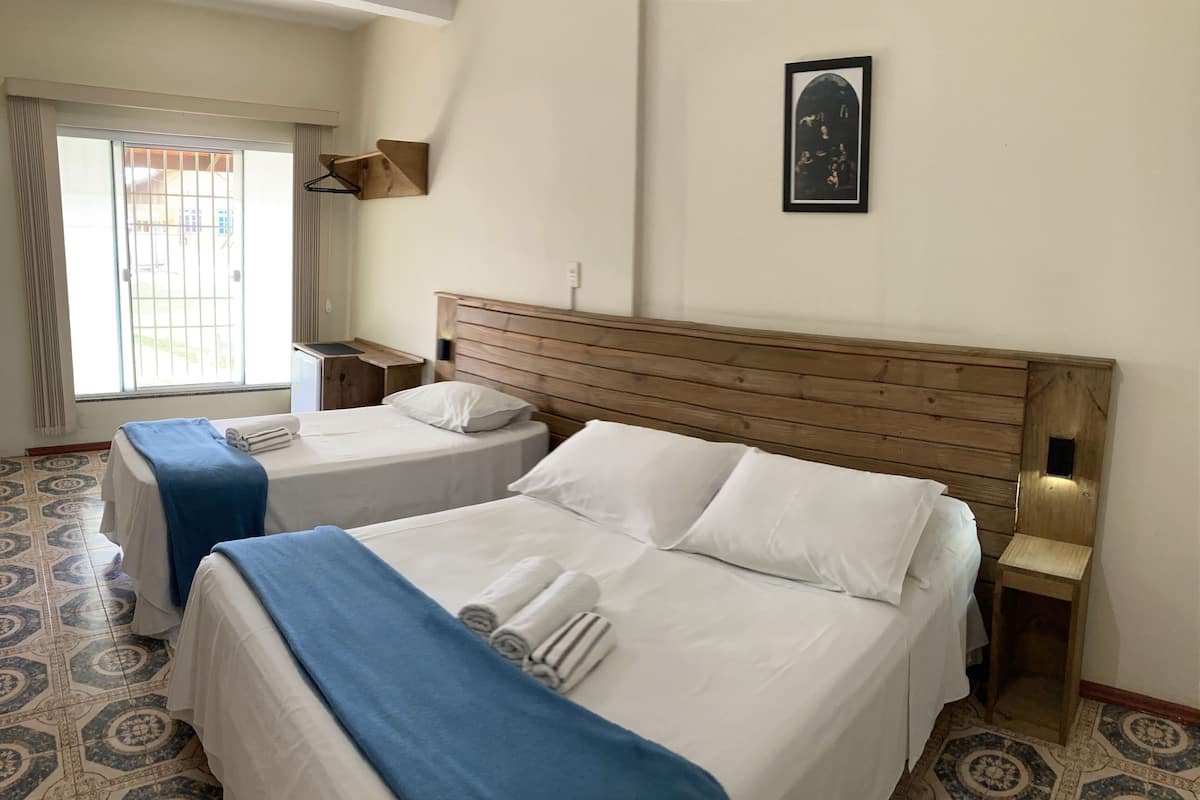 Een hotelkamer met twee bedden, een houten hoofdeinde, een klein tafeltje en een aan de muur hangend schilderij.