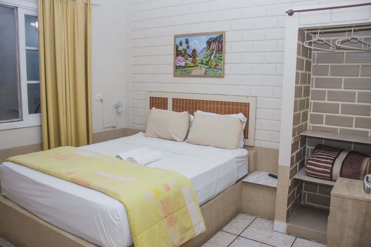 Een hotelkamer met een bed, een schilderij aan de muur en een metselwerk wand.