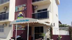 A hotel named 'Hotel Rocha Mar' with a covered entrance, a motorcycle parked outside, and potted plants around. - Hotel Rochamar (Penha)