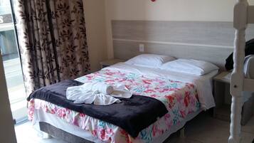 Una cama bien hecha con ropa de cama floral, un cabecero de madera y un adorno de pared rojo y blanco.