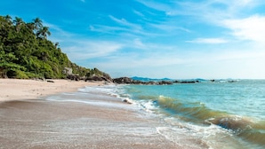 A beach with clear skies, calm waters, and a forested hillside. - Hotel Rochamar (Penha)