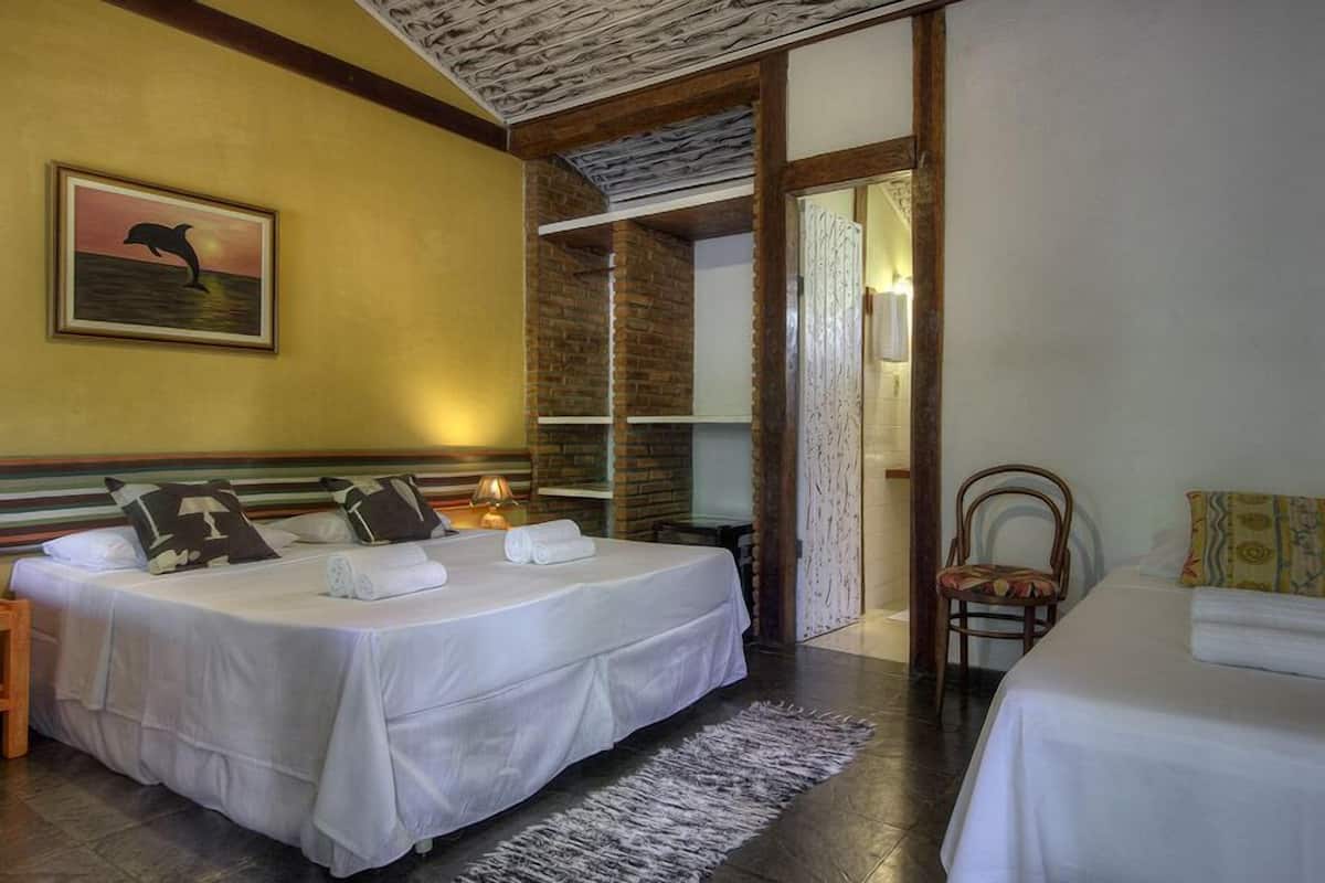 A hotel room with two beds, a painting on the wall, and a view through an open door.