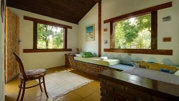 A room with a bed, a chair, a small table, and large windows.