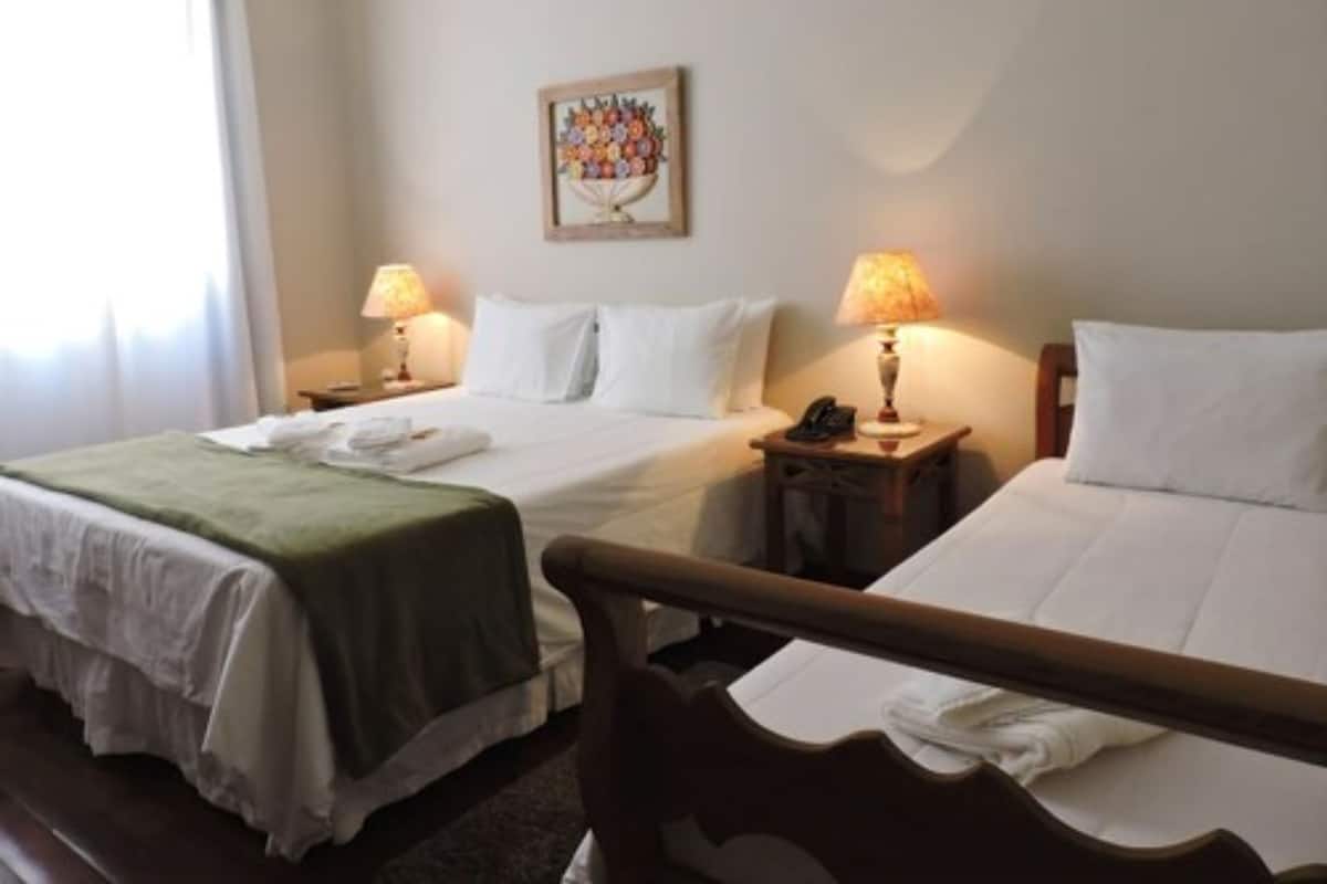 Ein Hotelzimmer mit zwei Betten, einem Bild an der Wand und zwei Nachttischlampen.