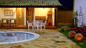 Un patio de piedra con piscina, mobiliario exterior y un horno de ladrillo.