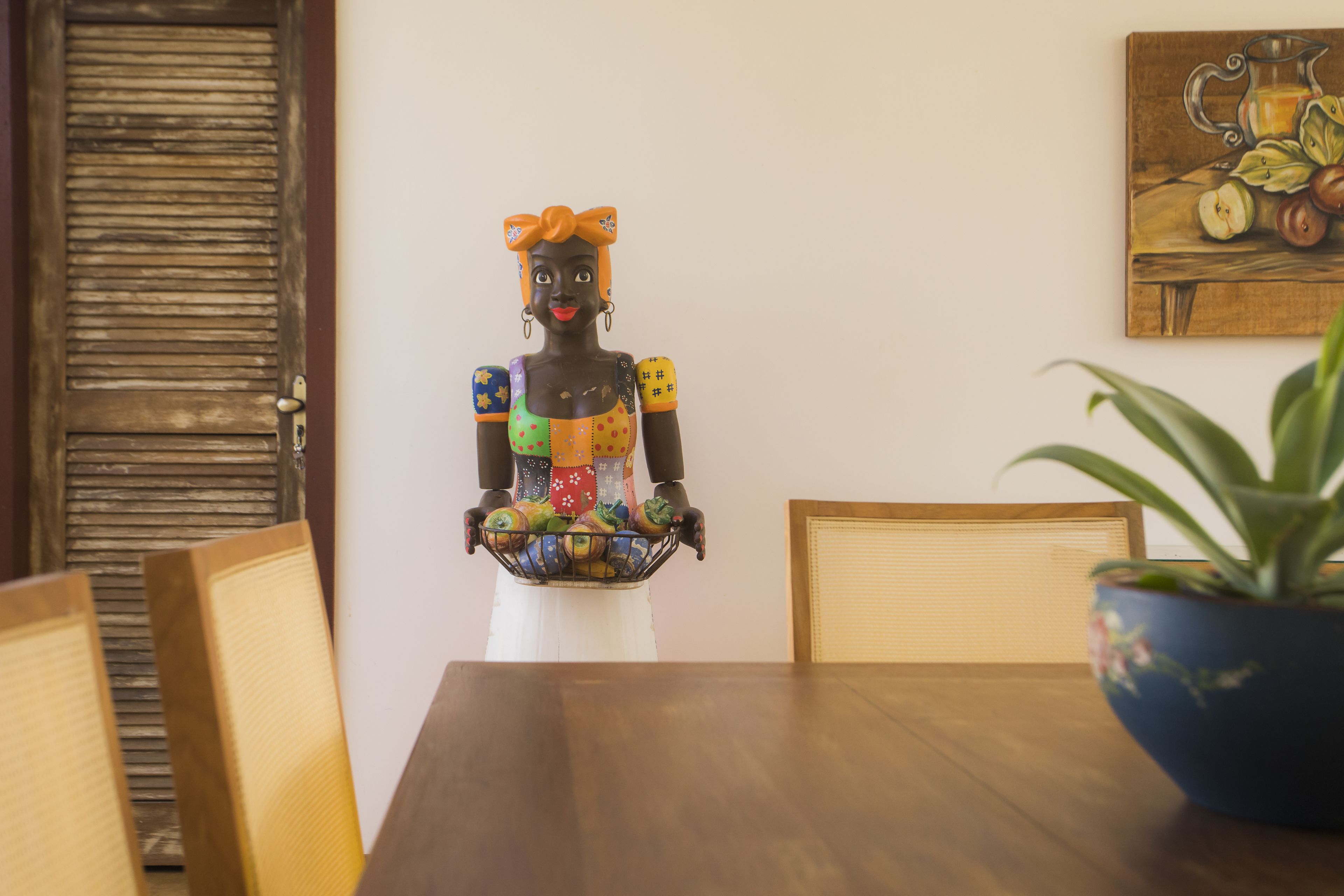 A dining area with a wooden table, chairs, a decorative statue, and a potted plant.