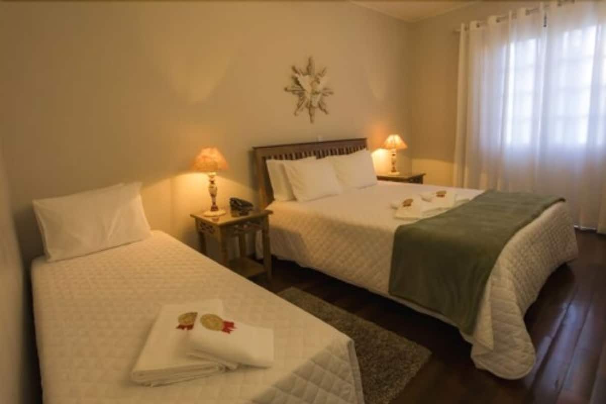Ein Hotelzimmer mit zwei Betten, jeweils mit weißer Bettdecke und Kissen, einem Nachttisch mit Lampe sowie einer Wanddekoration über den Betten.