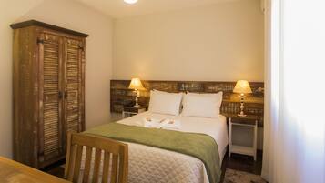 A bedroom with a bed, two bedside lamps, a wooden wardrobe, and a chair.