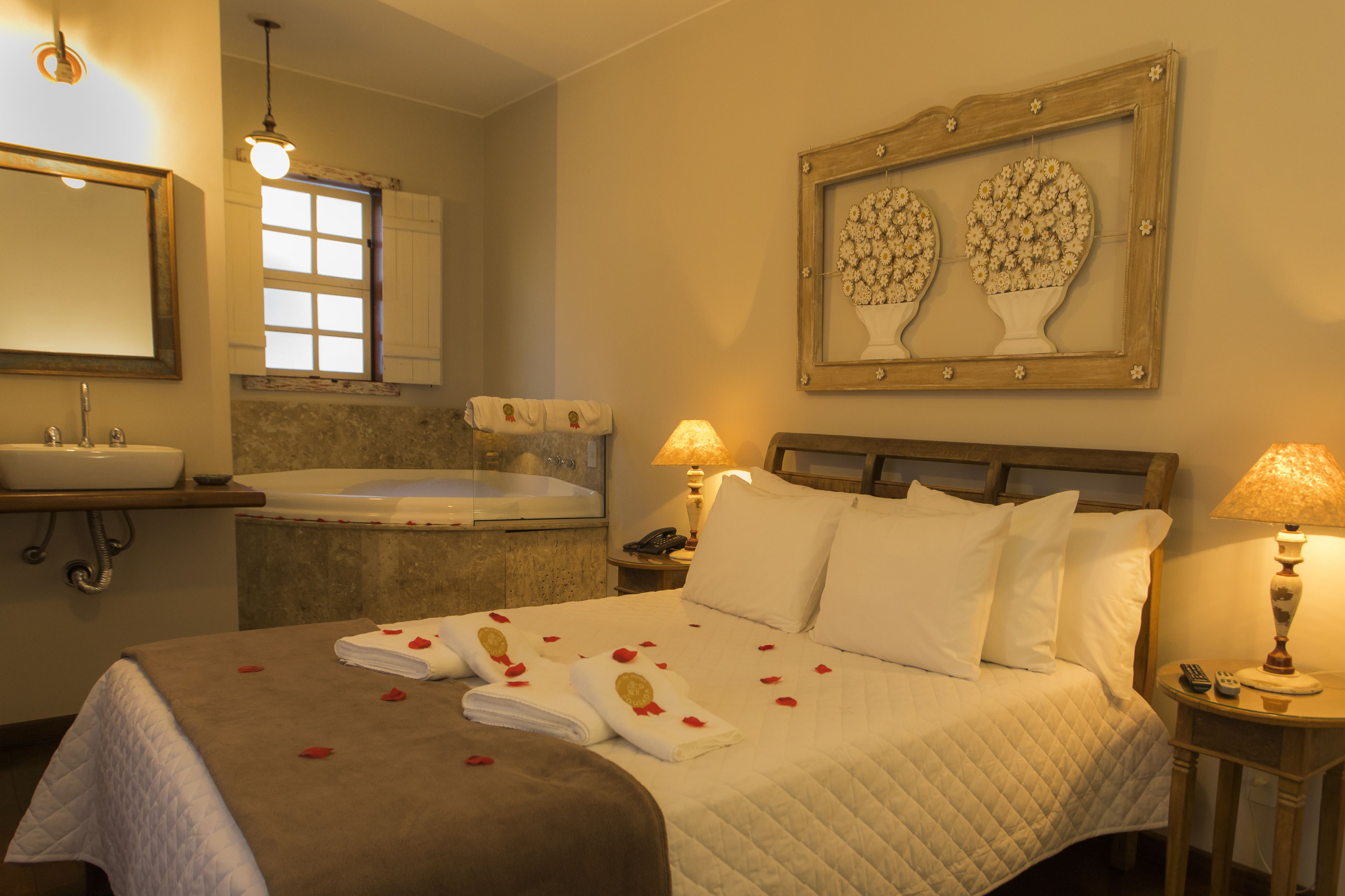 A hotel room with a bed, a bathroom with a bathtub, a sink, and a framed artwork on the wall.