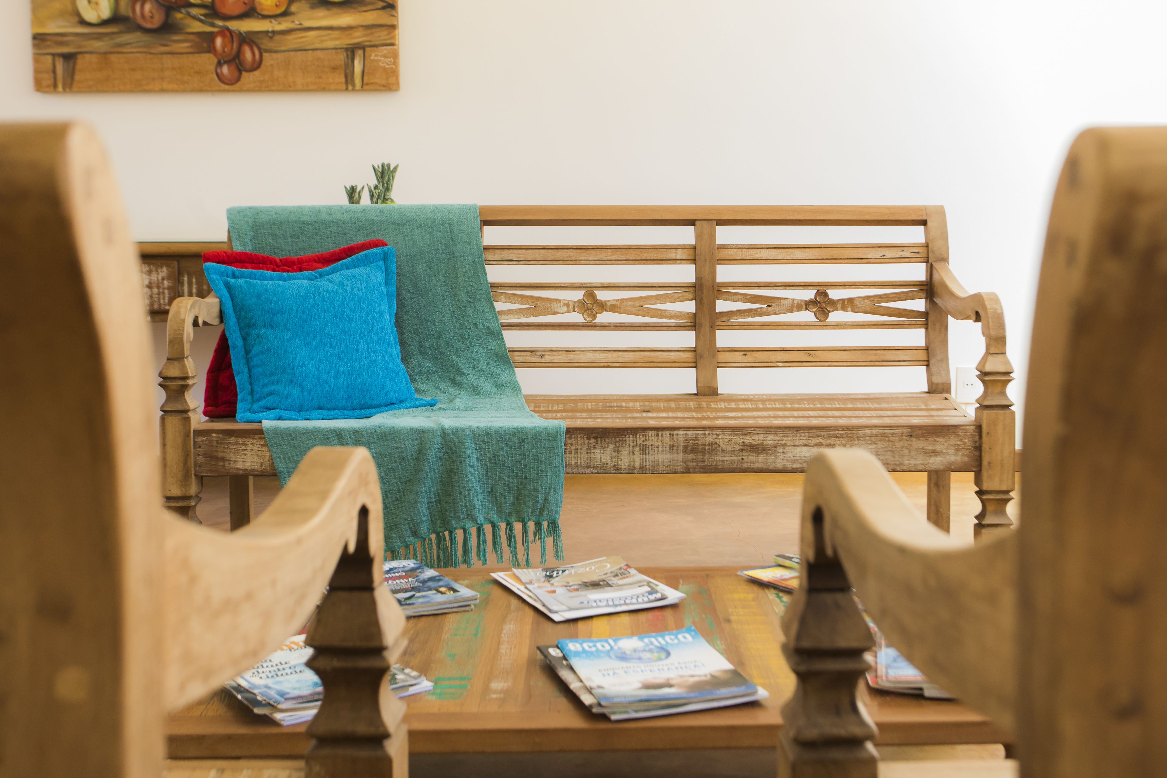 Un banco de madera con un cojín azul y una manta verde.