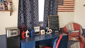 A room with a blue desk, a red chair, a coffee machine, a small fridge, and a sign indicating WiFi availability. - Blue Spruce Motel (North Platte)