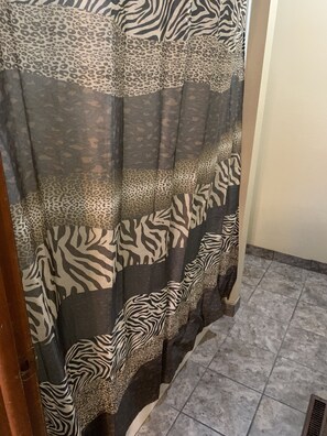 A bathroom with zebra-patterned shower curtains and a tiled floor. - Blue Spruce Motel (North Platte)