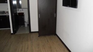 A room with a wooden floor, a dark door, and a small window. - Apartamento Quinta Paredes 036 (Bogotá)