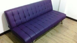A purple sofa in a room with wooden flooring and white walls. - Apartamento Quinta Paredes 036 (Bogotá)