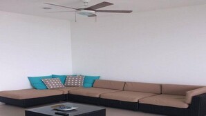 A living room with a sectional sofa, a coffee table, and a ceiling fan. - Apartamentos Puerto Valero 008 (Coveñas)