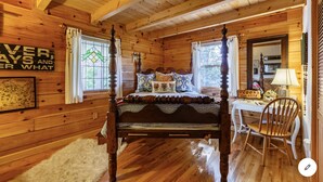 A four-poster bed in a wooden cabin room with a rustic decor, including a map and a sign on the wall.