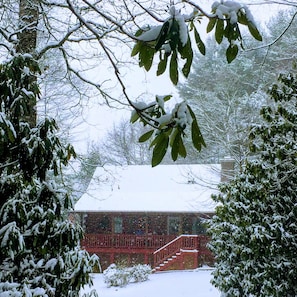 Una casa de fachada roja, una escalera visible y un paisaje cubierto de nieve.