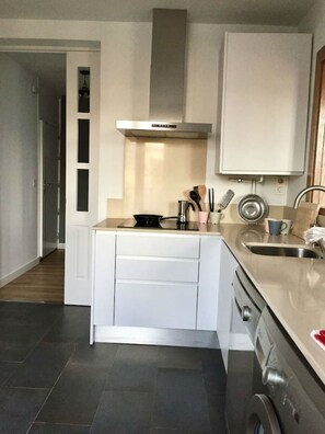 A compact kitchen with white cabinets, a stainless steel range hood, and a built-in oven.