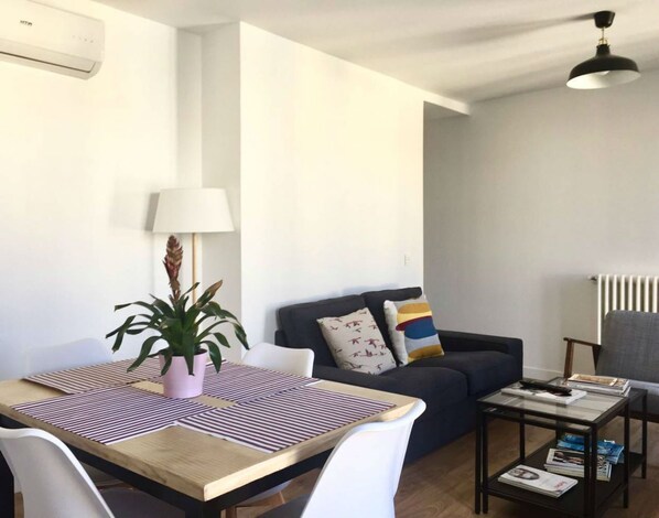 A modern living room with a dining table, sofa, and a coffee table with magazines.