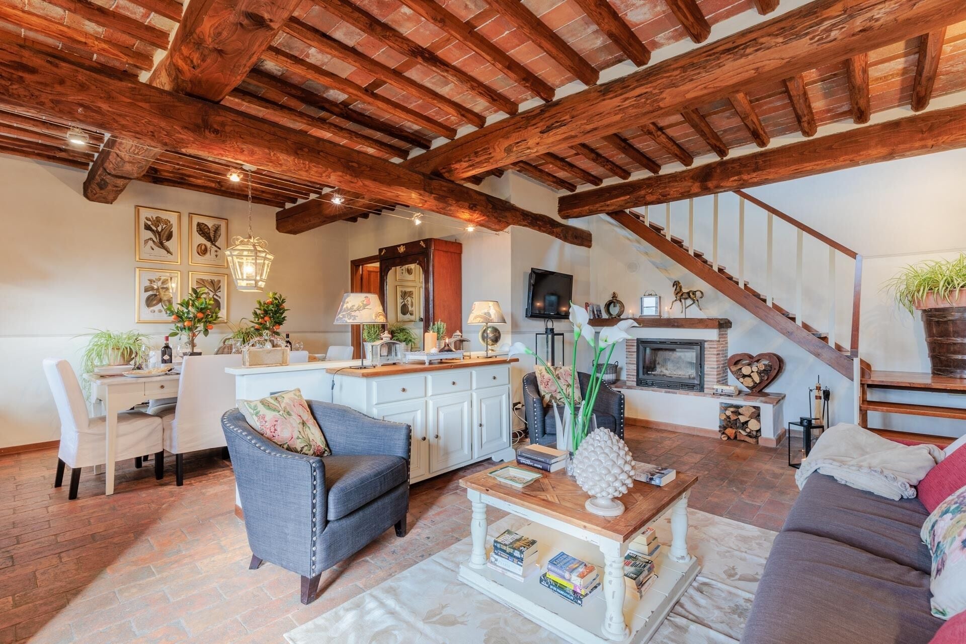 A cozy living room with a fireplace, a dining area, and a staircase leading to an upper level.