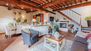 Un salon chaleureux avec une cheminée, un coin repas et un escalier menant à l’étage supérieur.