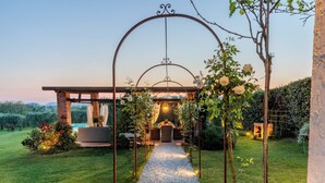 Une terrasse de jardin agrémentée d’une pergola, d’une table à manger et, au fond, d’une piscine.