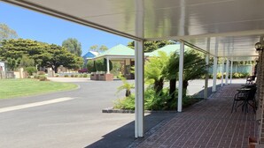 A covered outdoor area with brick flooring, a glass table, and black chairs. - Arthur Phillip Motor Inn (Cowes)