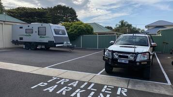 A trailer parked in a designated trailer parking area with a white SUV in front.