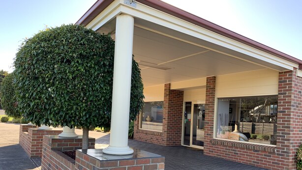 A building entrance with a covered porch, brick walls, and a well-maintained hedge. - Arthur Phillip Motor Inn (Cowes)