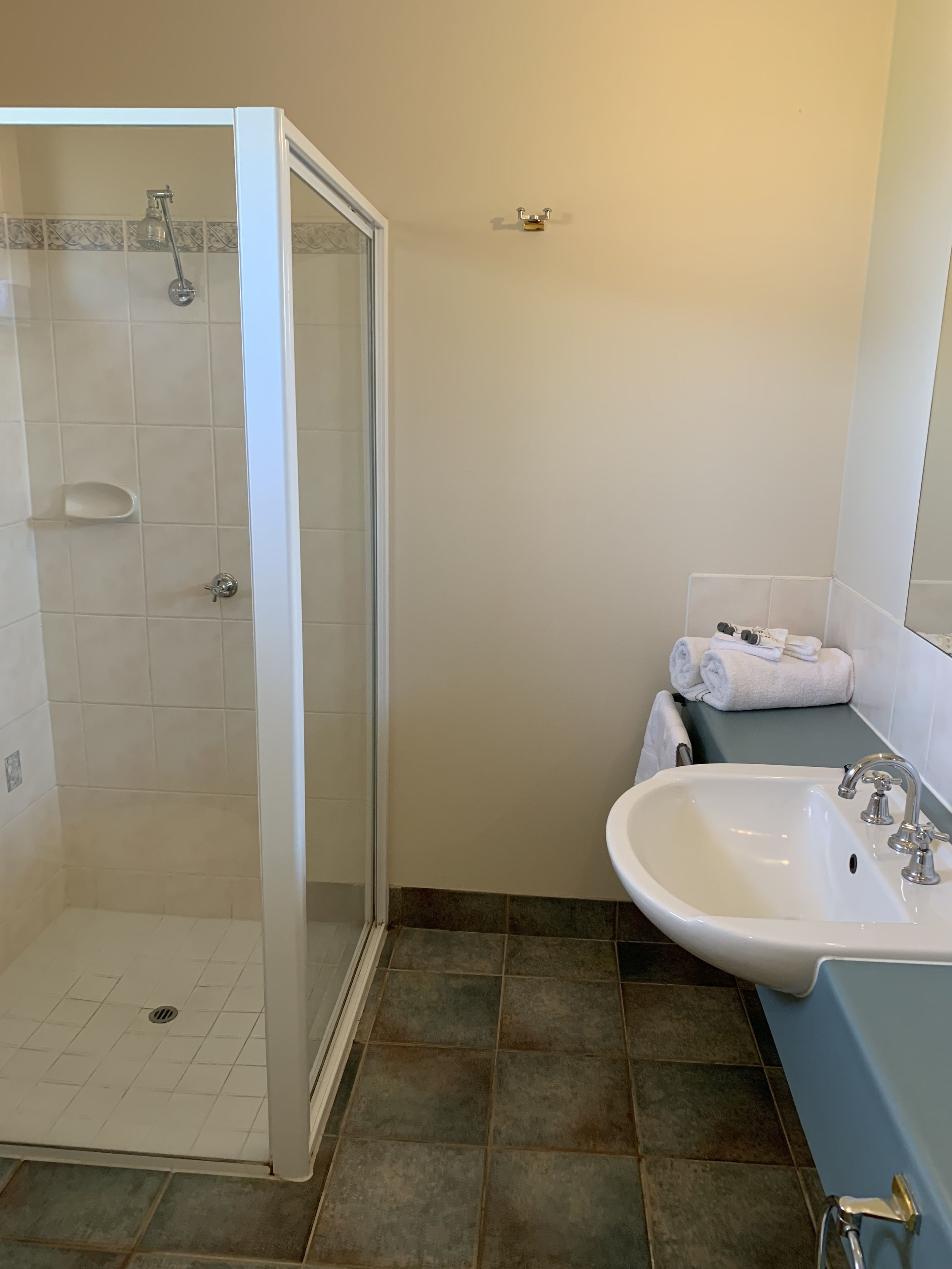 A bathroom with a shower, sink, and a towel rack.