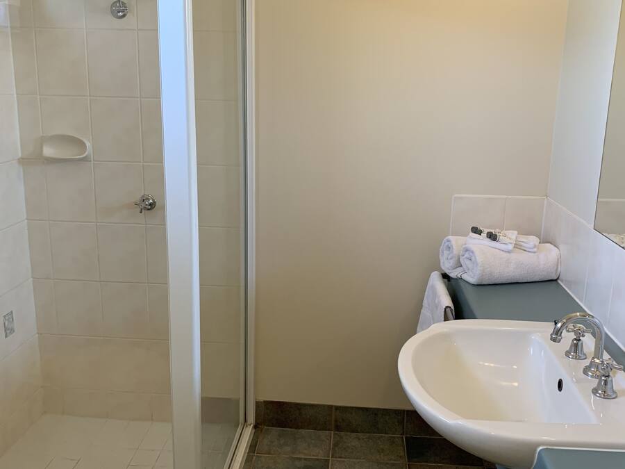 A bathroom with a shower, sink, and a towel rack.