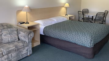 A hotel room with a bed, a sofa, a table with chairs, and two bedside lamps.