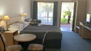 A hotel room with two beds, a desk with a TV, a small round table, and chairs. - Arthur Phillip Motor Inn (Cowes)