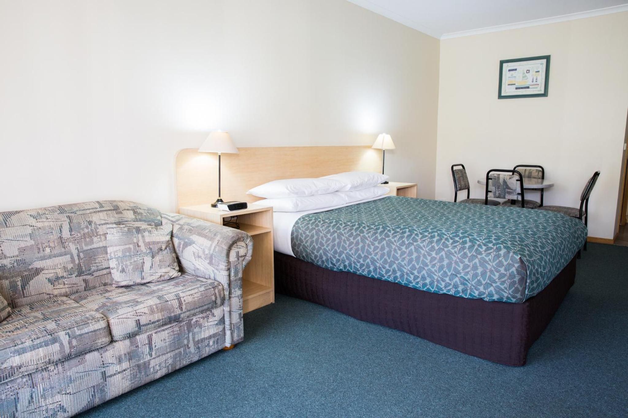 A hotel room with a bed, a sofa, a desk, and a chair.