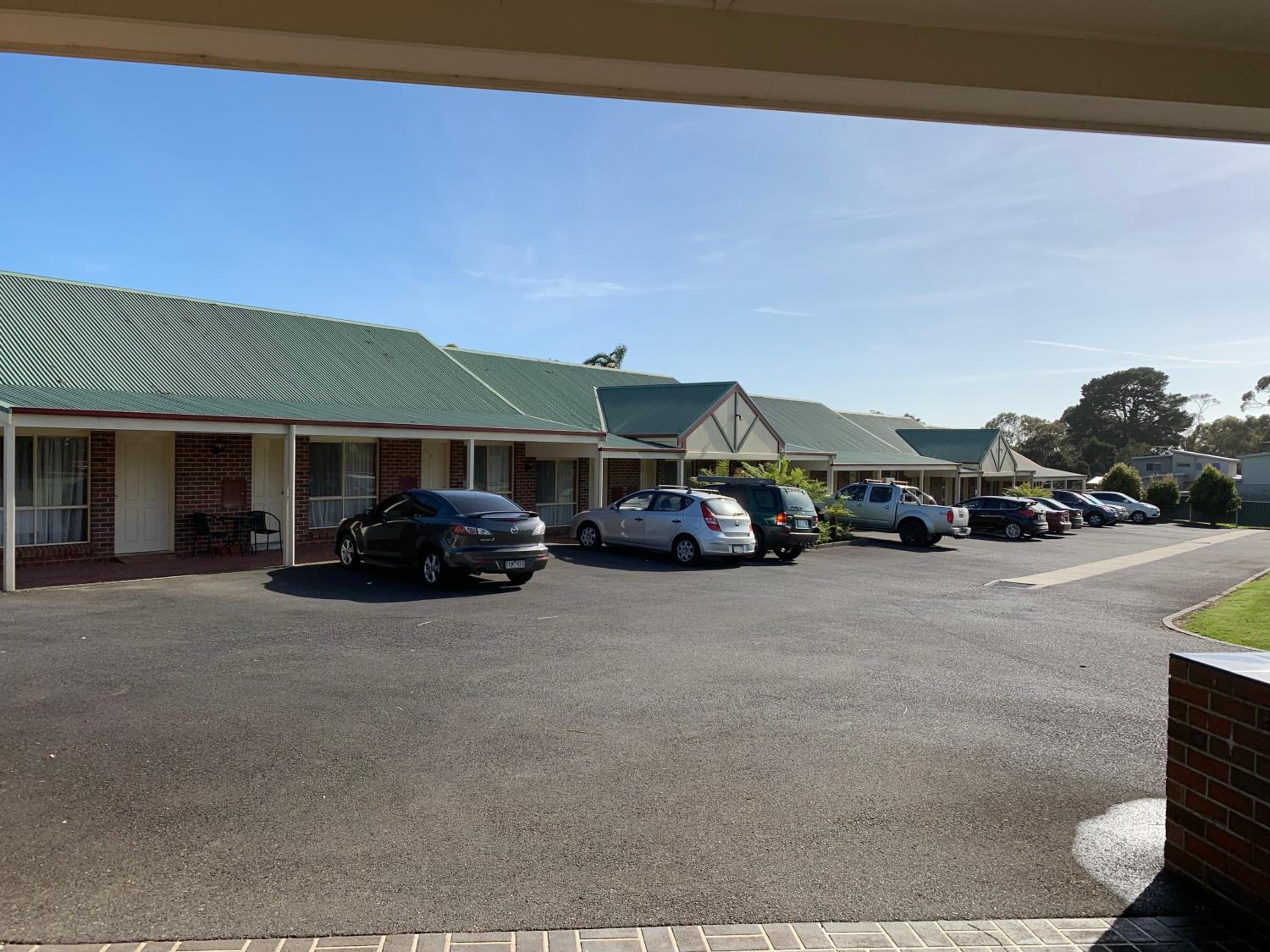 A motel with multiple rooms, a parking lot, and a clear sky.