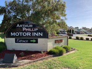 A sign for Arthur Phillip Motor Inn with an entrance arrow.