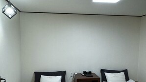 A small, clean room with two beds, a nightstand, a desk, and a ceiling light. - High Valley Hotel (Jeongseon)